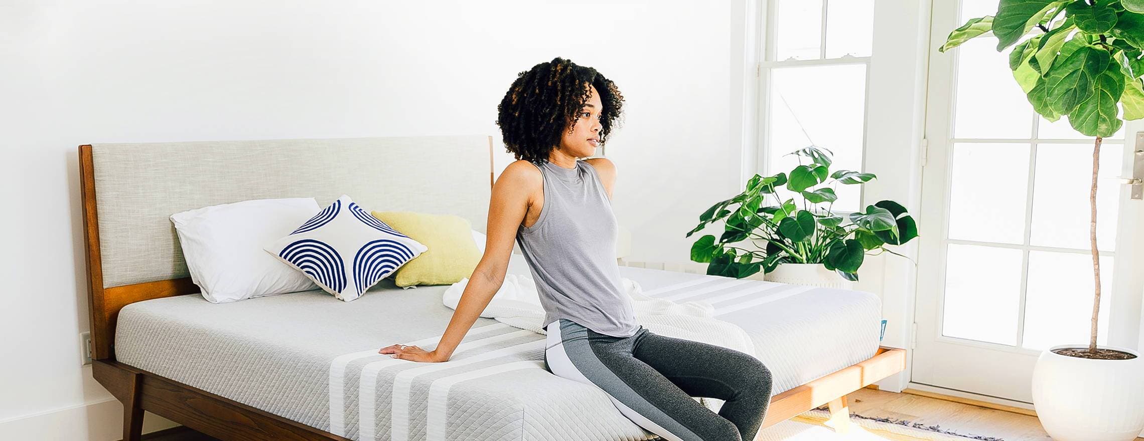 A lady sitting on a Leesa mattress in a decorated room