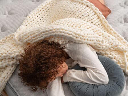 A lady sleeping under a Leesa weighted blanket on a mattress