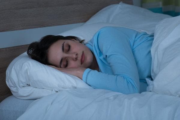 A lady sleeping on her side on a leesa mattress and pillow 2 small