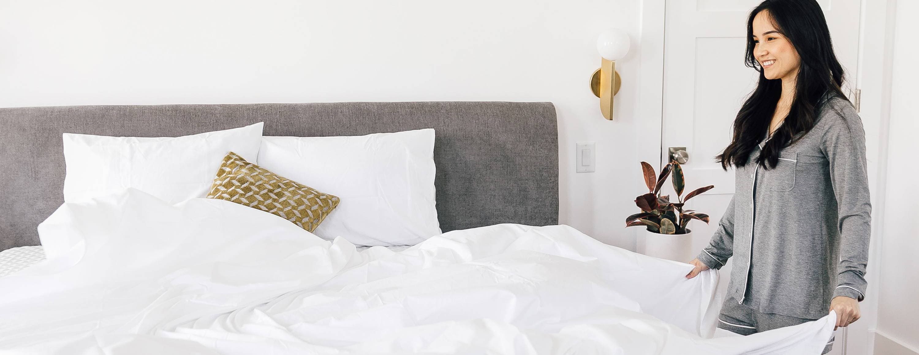 A lady fluffing the sheets on a Leesa mattress