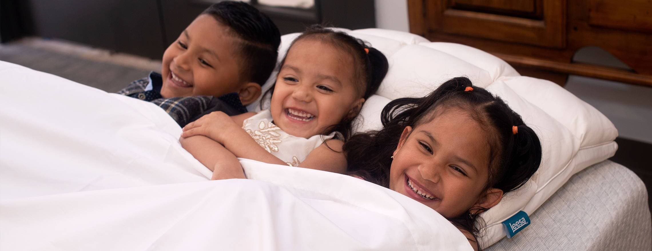 Three happily smiling kids in a Leesa bed