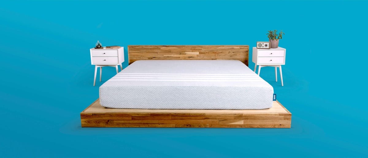 a_leesa_mattress_on_a_flat_all_wood_frame_displayed_with_nightstands_and_blue_background