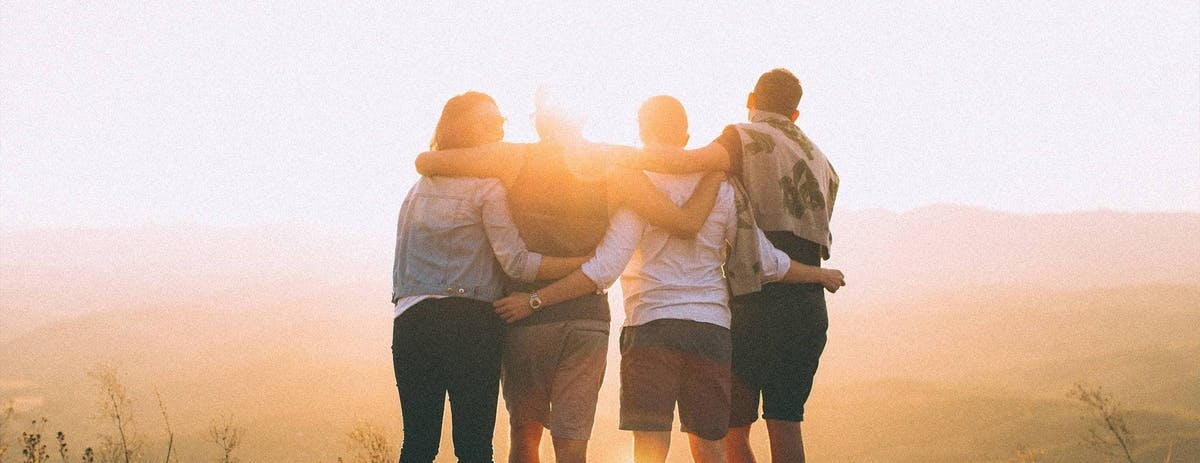 group_of_people_standing_arm_in_arm_looking_into_the_sunset