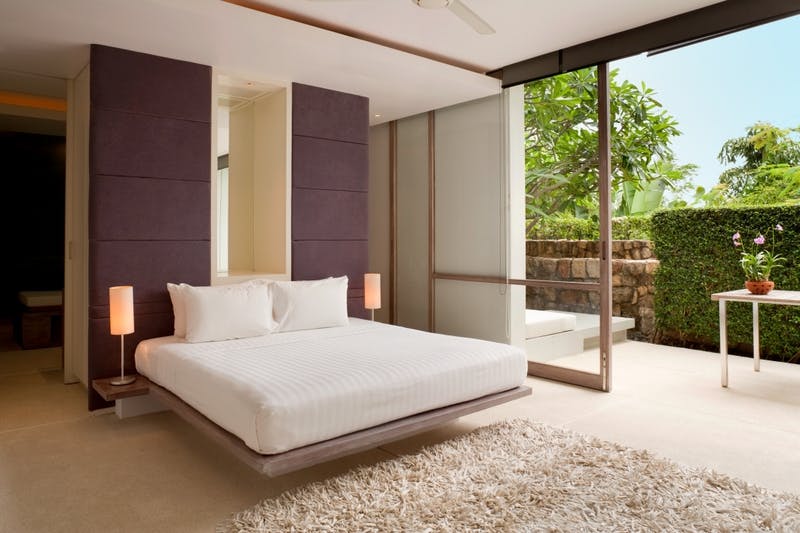 Interior of a bedroom with a platform bed, white duvet, and neutral accents