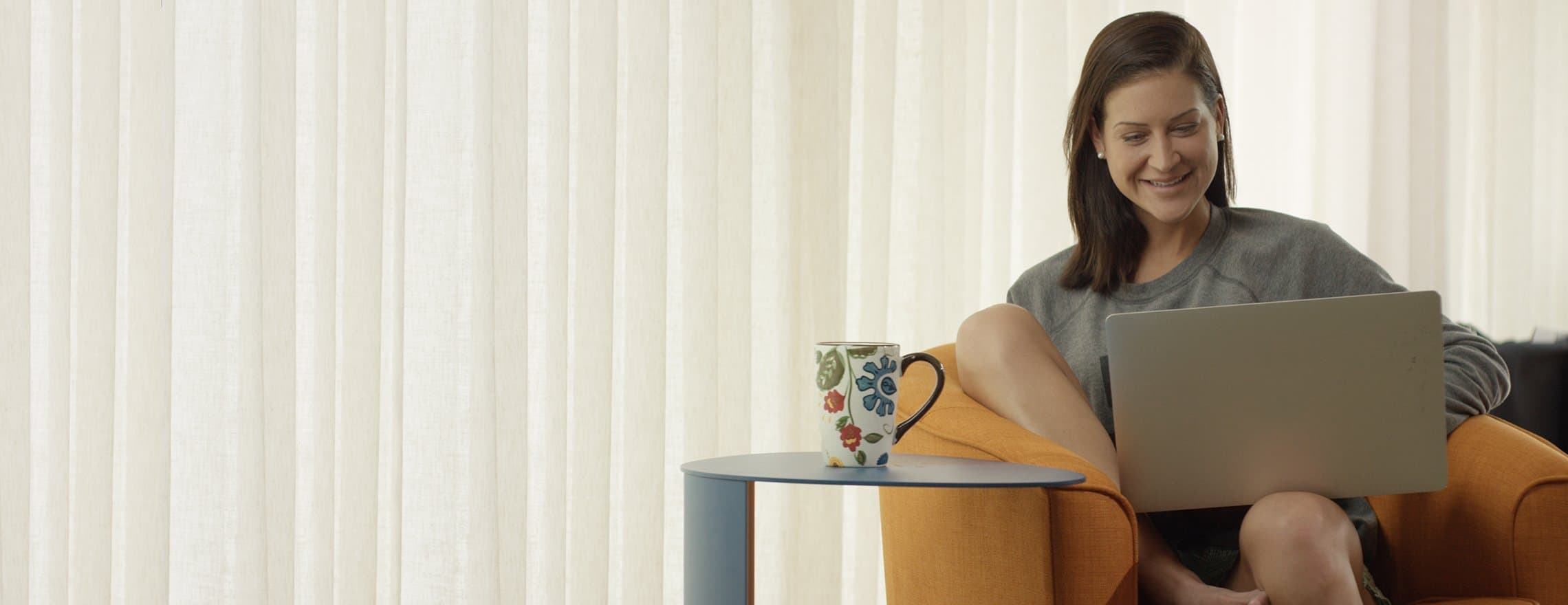 A lady sitting on a chair with a laptop looking at the Leesa mattress site