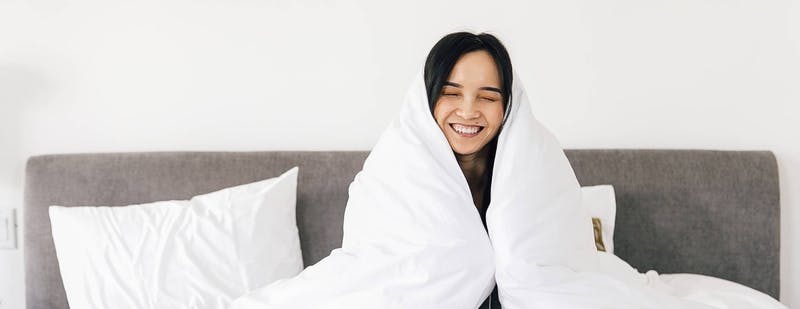 smiling_lady_surrounded_in_white_comforter_on_a_leesa_mattress