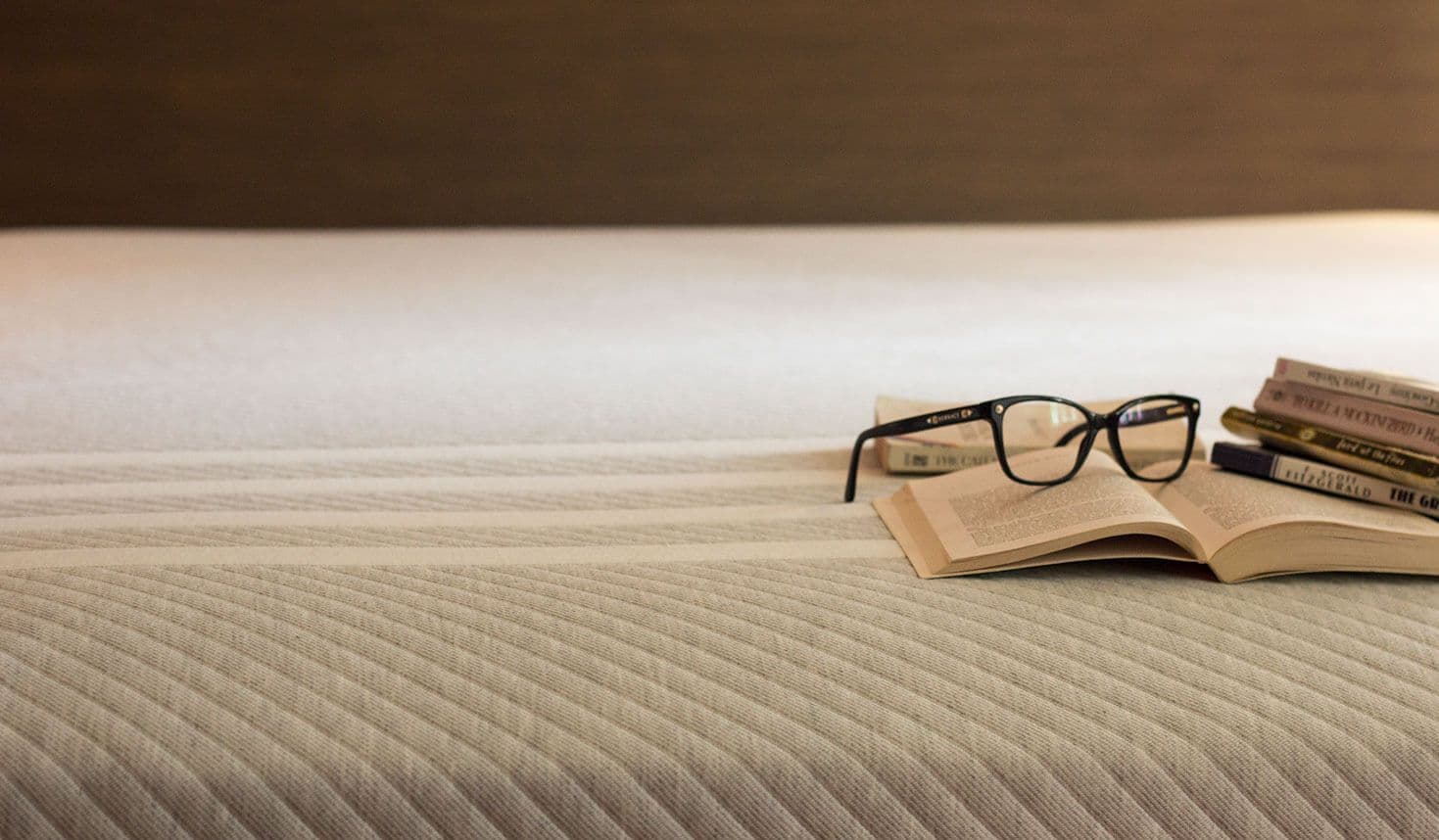 A Leesa mattress with books and reading glasses
