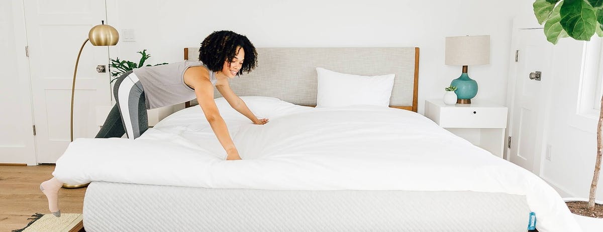 lady_spreading_out_a_white_comforter_on_a_leesa_mattress_in_bedroom