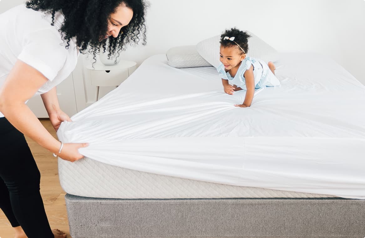 mother putting on a mattress protector with baby