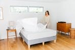 lady_fluffing_sheets_on_a_leesa_mattress_in_a_decorated_room