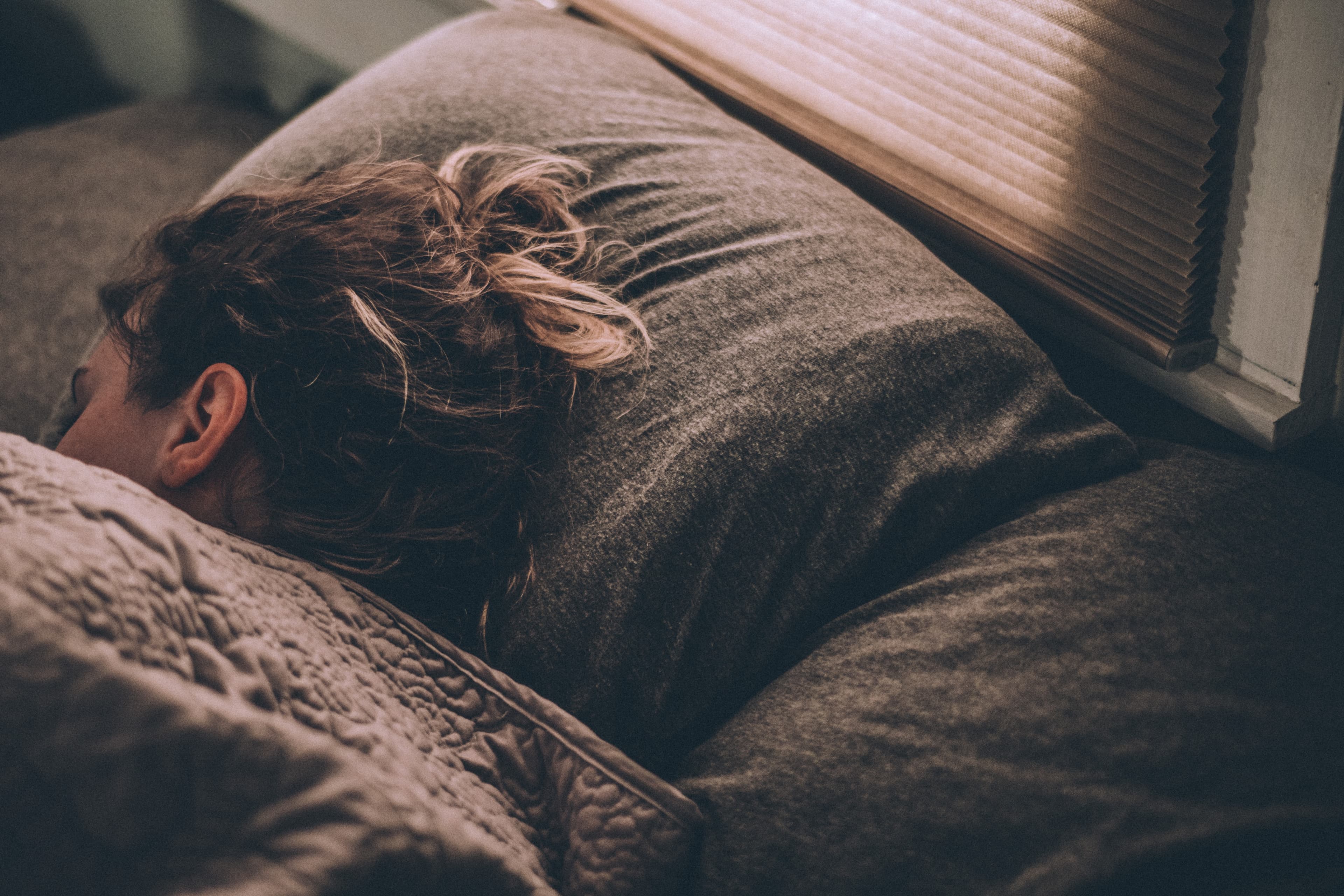 A woman sleeping on a Leesa bed under blankets