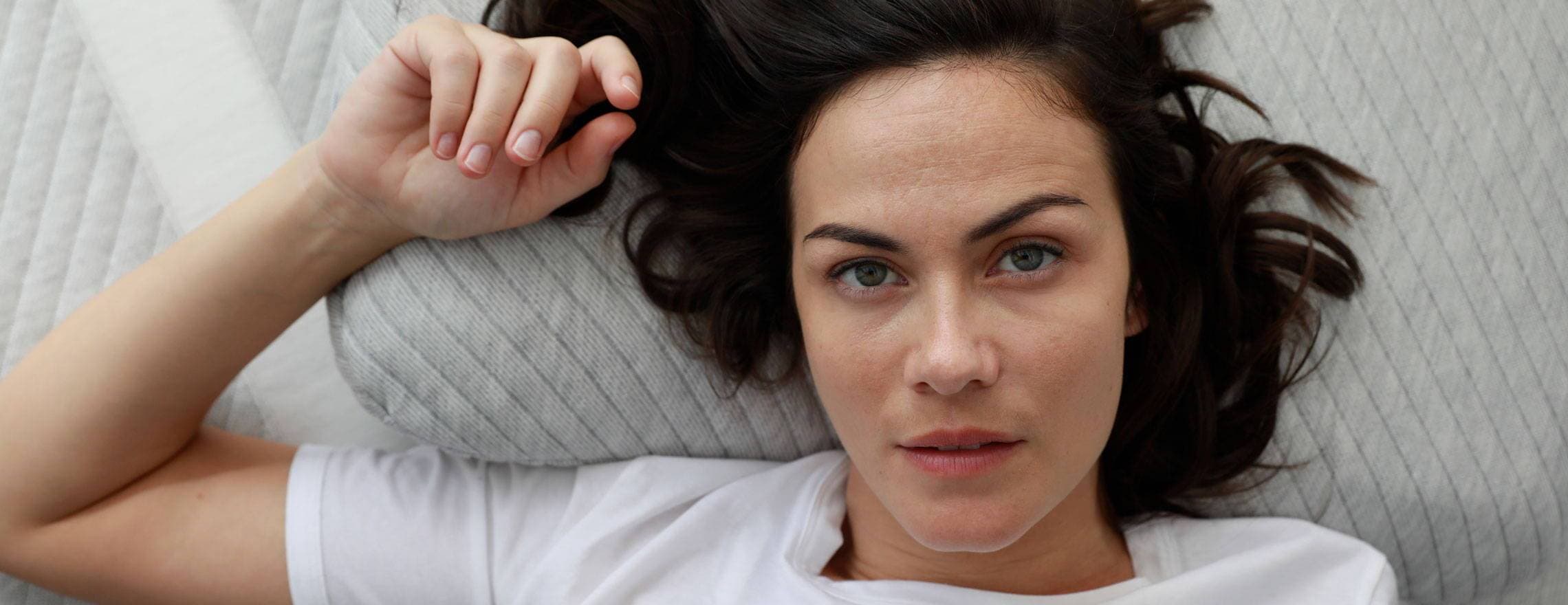 Lady lying on a Leesa pillow and mattress.