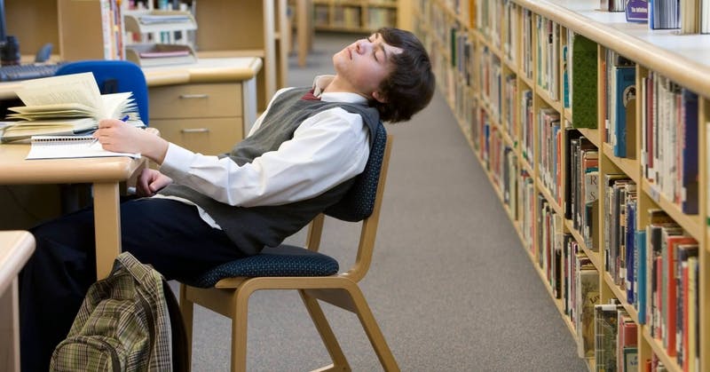 student_sleeping_in_a_chair_in_the_library